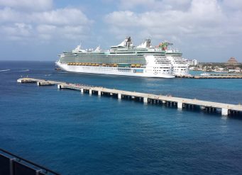 Cruise ship docked at sunny resort.