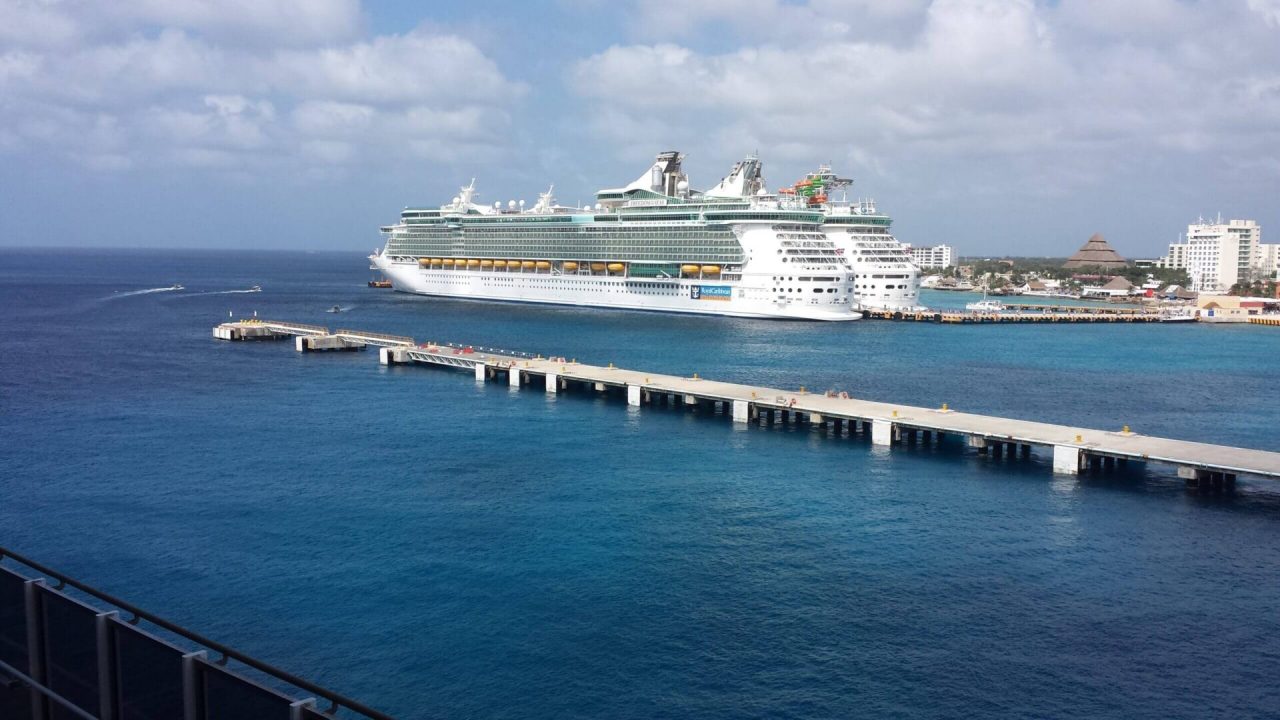 Cruise ship docked at sunny resort.