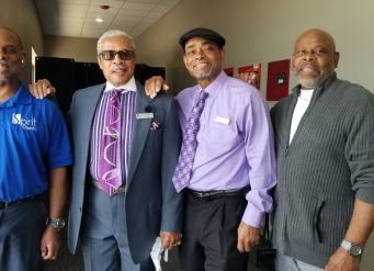 Four men standing together smiling