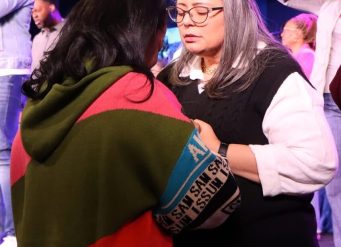Two women praying together on stage