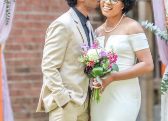 Bride smiling while groom kisses her cheek