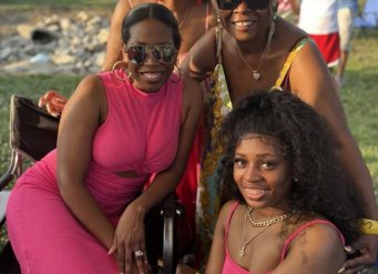 Four smiling women wearing pink at outdoor gathering