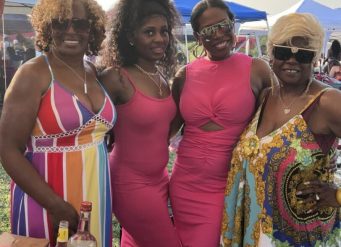 Four smiling women in colorful dresses