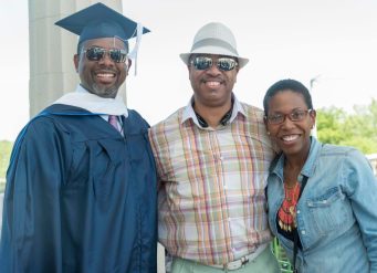 Smiling graduate with two family members