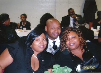 Three smiling adults posing at indoor gathering