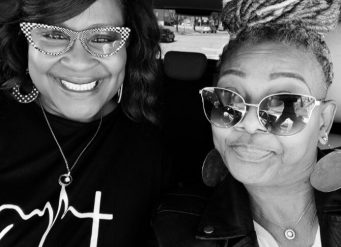 Two women smiling in car wearing sunglasses
