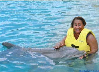 Woman petting dolphin in blue water.