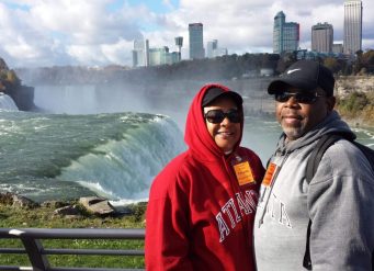 Couple at Niagara Falls with city backdrop.